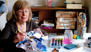 Jane Notides-Benzing working in her “studio” — the kitchen at her Rochester home.